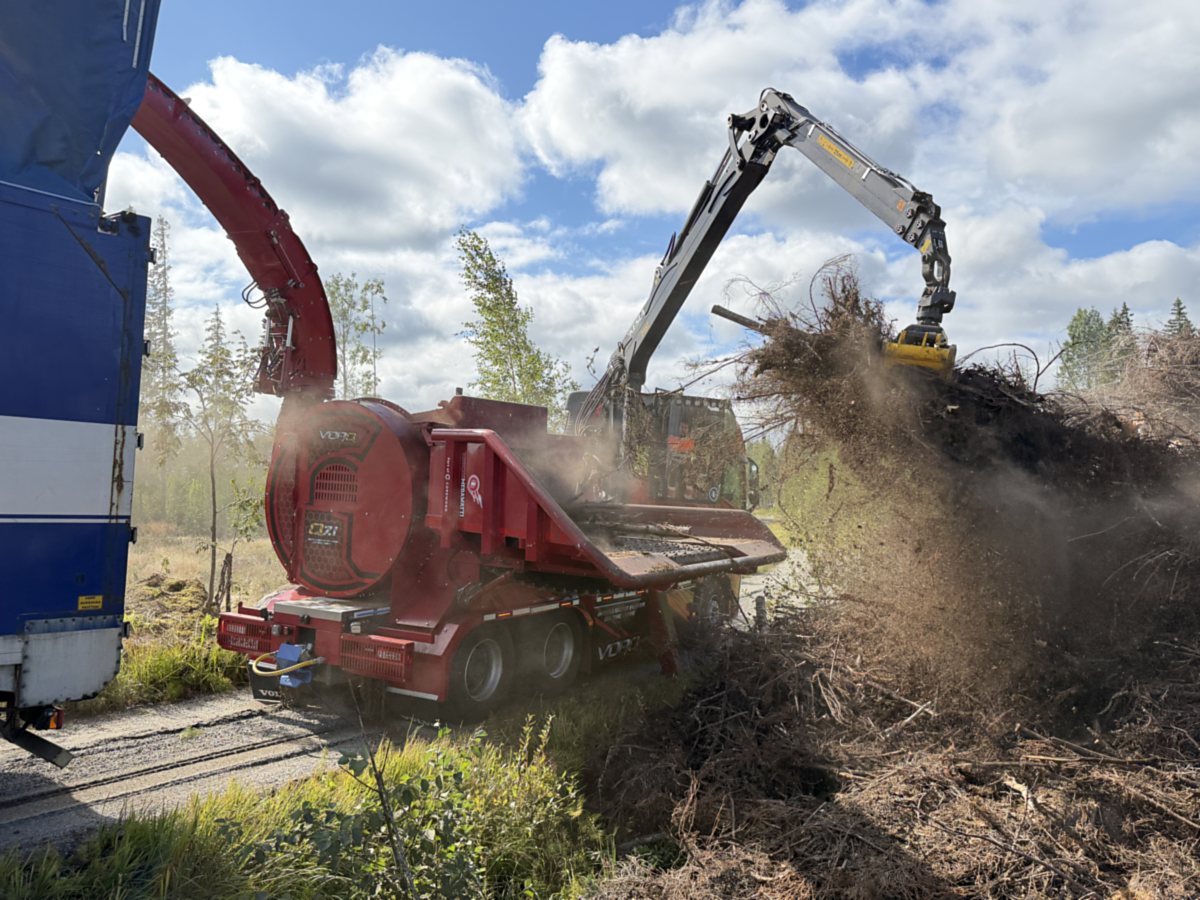 VORQ Q7.1 hakettaa hakkuutähdettä kuorma-auton kyytiin metsätiellä.